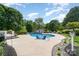 Landscaped backyard with an in-ground pool, patio, lounge chairs, and mature trees at 130 Hopedale Ct, Mooresville, NC 28117