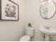 Cozy powder room with pedestal sink, round mirror, and decorative wall art at 130 Hopedale Ct, Mooresville, NC 28117