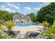 Beautiful in-ground pool with surrounding patio, lounge chairs, lush landscaping, and home exterior at 130 Hopedale Ct, Mooresville, NC 28117