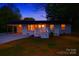 Inviting single-story home with a white brick facade, front porch, covered carport, and warm interior lighting at dusk at 1341 Hopewell Rd, Rock Hill, SC 29730