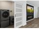 Modern laundry room featuring stacked washer and dryer, sliding door, and fireplace with mounted TV at 1341 Hopewell Rd, Rock Hill, SC 29730
