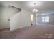 Spacious carpeted living area with staircase and entry to half-bathroom at 1430 Eastway Dr, Dallas, NC 28034
