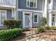 Close-up of townhome entrance with white door, manicured shrubs, and gray siding, creating a charming first impression at 1568 Cleveland Ave, Charlotte, NC 28203