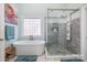 Bright bathroom featuring a soaking tub, glass-enclosed shower, and a window for natural light at 16636 Flintrock Falls Ln, Charlotte, NC 28278