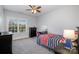 Bedroom with a ceiling fan, desk, and dresser bathed in natural light from a large window at 16636 Flintrock Falls Ln, Charlotte, NC 28278