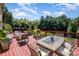 A spacious deck features an outdoor dining table, lounge chairs, and a lush green backyard view at 16636 Flintrock Falls Ln, Charlotte, NC 28278