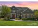 Elegant two-story brick home with a well-manicured lawn, a red front door, and beautiful landscaping at 16636 Flintrock Falls Ln, Charlotte, NC 28278
