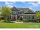 Charming two-story brick home featuring a red front door, manicured landscaping, and a well-maintained lawn at 16636 Flintrock Falls Ln, Charlotte, NC 28278