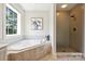 Bright bathroom featuring a soaking tub with tile surround, a separate shower, and a window at 1824 Hall Ave, Charlotte, NC 28205