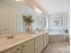 Bright bathroom featuring double vanity sinks, a large mirror, and a soaking tub with tile surround at 1824 Hall Ave, Charlotte, NC 28205