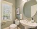 Cozy half-bathroom with unique round mirror, pedestal sink and modern toilet at 1824 Hall Ave, Charlotte, NC 28205