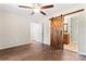 Bedroom with wood-look flooring, ceiling fan, and bathroom access with rustic sliding door at 2615 Toddville Rd, Charlotte, NC 28214
