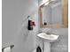 Stylish half-bathroom with a pedestal sink, decorative mirror, and neutral gray walls at 314 Wave Crest Dr, Tega Cay, SC 29708