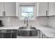 Close-up of a stainless steel farmhouse sink, marble countertops, and white cabinets in the kitchen at 3612 Cobbleridge Dr, Charlotte, NC 28215