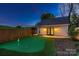 A backyard featuring a putting green, wooden fence, and a detached garage with double doors and exterior lighting at 3709 Commonwealth Ave, Charlotte, NC 28205