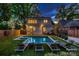 Night view of the backyard featuring an in-ground pool, patio area, and lush landscaping at 3709 Commonwealth Ave, Charlotte, NC 28205