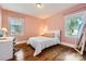 Bright bedroom with hardwood floors features two windows and a stylish decor at 3709 Commonwealth Ave, Charlotte, NC 28205