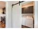 Convenient laundry room with sliding barn door, front load washer/dryer, and upper cabinets at 3709 Commonwealth Ave, Charlotte, NC 28205