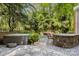 Backyard featuring hot tub, stone patio, outdoor kitchen and mature trees at 3819 Gleneagles Rd, Charlotte, NC 28210