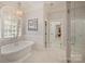 Luxurious bathroom featuring a soaking tub, chandelier, and a glass shower, offering a spa-like experience at 3819 Gleneagles Rd, Charlotte, NC 28210