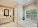 Bright bathroom features a large soaking tub with window views, plus double sink and tiled floors at 3819 Gleneagles Rd, Charlotte, NC 28210