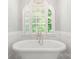 Bright bathroom featuring a standalone tub beneath a large arched window with white shutters at 3819 Gleneagles Rd, Charlotte, NC 28210