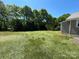 Large backyard with a sunny lawn near mature trees and home at 427 W Whitley St, Norwood, NC 28128