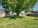 Large, grassy backyard with mature tree, playground, and privacy fence offers ample space for recreation at 4665 Madeline Dr, Rock Hill, SC 29732