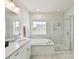Bright bathroom features a soaking tub, glass shower, and double vanity with marble countertops at 6433 Raffia Rd, Charlotte, NC 28277