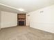 Spacious carpeted basement featuring a brick fireplace and a single light fixture at 6745 Thermal Rd, Charlotte, NC 28211