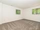 Neutral carpeted bedroom featuring two black framed windows and white walls at 6745 Thermal Rd, Charlotte, NC 28211