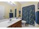 Bright bathroom with a cherry vanity, matching framed mirror, and a cheerful shower curtain at 705 Normandy Rd, Mooresville, NC 28117