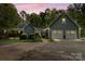 This cozy home has a two-car garage, set amidst a backdrop of mature trees at dusk at 705 Normandy Rd, Mooresville, NC 28117