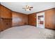 Cozy living room with carpet, wood paneling, brick fireplace, and ceiling fan with view to kitchen at 71 14Th Se St, Hickory, NC 28602