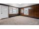 Cozy living room featuring wood paneling, neutral carpet, and large windows providing ample natural light at 71 14Th Se St, Hickory, NC 28602