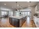 Open-concept kitchen with an island, modern lighting, and stainless steel appliances, creating a stylish and functional space at 7157 Sumters Camp Trl, Indian Land, SC 29707