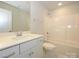 Well-lit bathroom with vanity, toilet, and shower-tub combo, all in neutral tones at 7185 Chamberlain Dr, Harrisburg, NC 28075