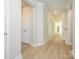 Bright hallway featuring light walls, contrasting white trim, and light laminate flooring at 7185 Chamberlain Dr, Harrisburg, NC 28075