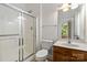 Bathroom featuring a glass-door shower, toilet, vanity with sink, and window at 7302 Yellowhorn Trl, Waxhaw, NC 28173