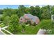 Aerial view of a brick home with a well-manicured lawn, mature trees, and black shutters on a sunny day at 7302 Yellowhorn Trl, Waxhaw, NC 28173