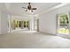 Large living room with a ceiling fan and large windows overlooking a landscaped yard at 7302 Yellowhorn Trl, Waxhaw, NC 28173