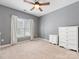 Carpeted bedroom with white dressers, a ceiling fan, and a window providing natural light at 7409 Tarland Ln, Charlotte, NC 28269