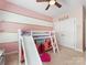 bedroom featuring a loft bed with slide and ladder, ceiling fan, and pink and white decor at 7409 Tarland Ln, Charlotte, NC 28269