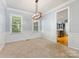 Elegant dining room with chair rail molding, neutral carpet, modern chandelier, and direct access to kitchen at 7409 Tarland Ln, Charlotte, NC 28269