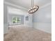 Expansive living room with plush carpeting, wainscoting, and natural light from the large windows at 7409 Tarland Ln, Charlotte, NC 28269