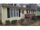 Charming yellow home features a brick foundation, black shutters, and a landscaped yard at 828 Williams St, Gastonia, NC 28052