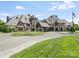 Grand home with lush landscaping and circular driveway featuring a fountain, stone accents and covered portico at 8710 Chewton Glen Dr, Waxhaw, NC 28173