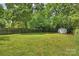 Lush backyard featuring a large lawn, mature trees, and a storage shed at 908 Academy St, Charlotte, NC 28205