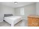 Cozy bedroom featuring light grey walls, modern flooring, and a comfortable queen-sized bed with white linens at 103 Moore Ave, Mount Holly, NC 28120