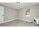 Clean, bright bedroom with light grey walls, wood-look floors, and an abundance of natural light at 103 Moore Ave, Mount Holly, NC 28120